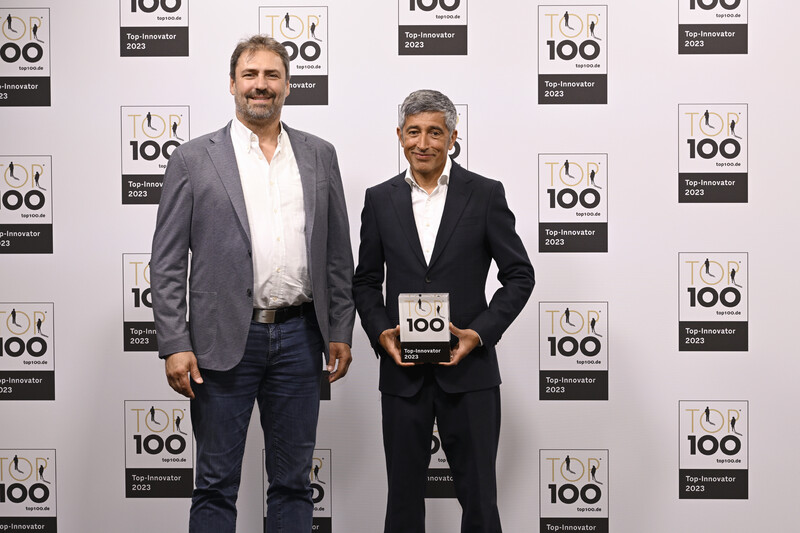 Michael Düren, Leiter der IT der SIGMETA, nimmt lächelnd den TOP 100 Preis von Moderator Ranga Yogeshwar bei der Preisverleihung entgegen